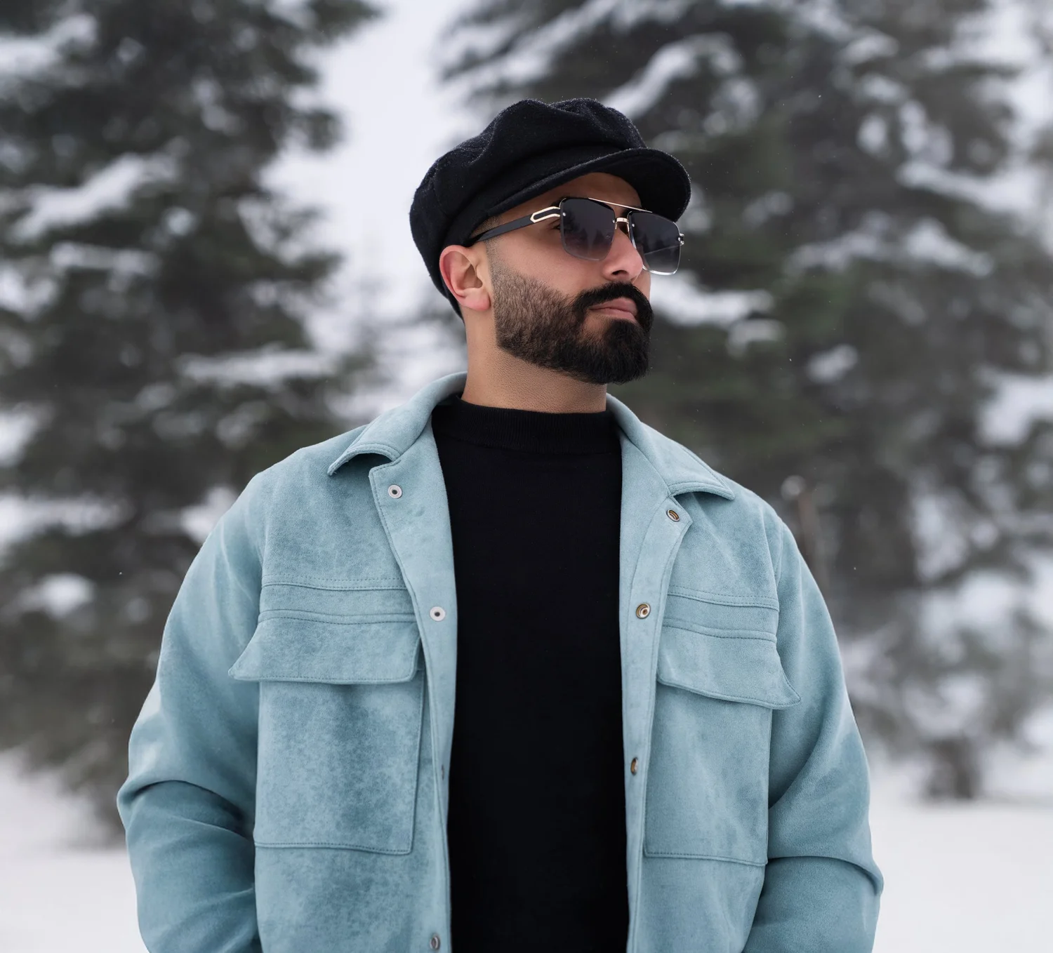 Mann mit Mütze, Sonnenbrille und hellblauer Jacke im Schnee
